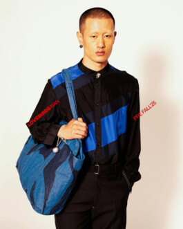 Sachit Gurung in a black and blue diagonal panel shirt, carrying a large blue printed tote bag for Lovebirds Men Pre-Fall 2025 campaign by A Little Fly 
