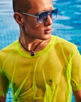 Model Sachit Gurung wearing blue-tinted sunglasses and a sheer neon green top, posing poolside for the IDÉE Dippers Edit campaign. 