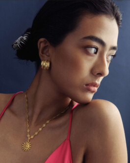 Medhavi Chettri in a pink strappy dress wearing a gold sun pendant necklace and chunky gold hoop earrings for Olio campaign 
