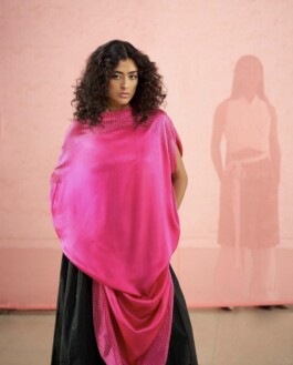 Medhavi Chettri wears a bold hot pink draped top with a black skirt against a blush pink backdrop for The Galleries campaign 