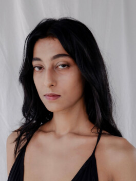 Akriti Jha close-up model digitals with natural makeup and black outfit, studio backdrop, minimal styling. 