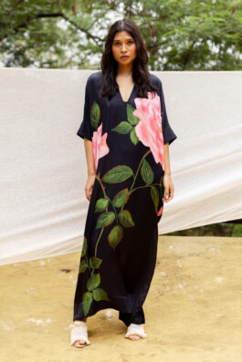 Merrylin Boro wearing a black silk kaftan with oversized pink floral print by Verandah, standing outdoors against a natural backdrop 