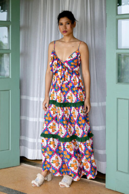 Merrylin Boro in a colorful floral ruffle maxi dress by Verandah, standing by pastel green doors 