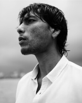 Close-up black and white portrait of ALF model Gaurav Gharu with wet hair and sand on his face at the beach 