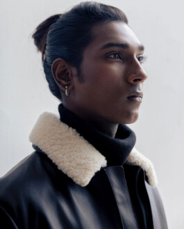 Close-up portrait of male model Savio Fedrick in a shearling-lined leather jacket and turtleneck 