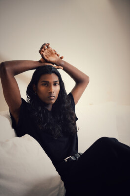Savio Fedrick, Indian model signed with A Little Fly (ALF), seated on white sofa in black outfit during natural light portrait session 