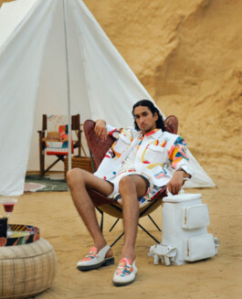 Male model lounging in a leather chair at a luxury desert campsite, wearing a vibrant co-ord set with printed loafers, photographed by Dhruvin Shah for Shivan & Narresh 