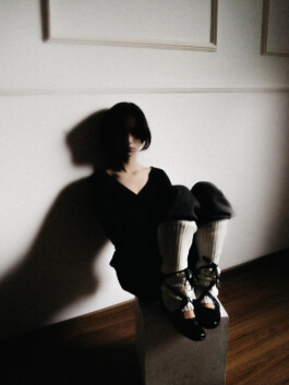 Model Tenzin Martha sits in shadows on a wooden floor wearing ballet-style leg warmers in an editorial shot by Sameer Khatri for A Little Fly modeling agency India 