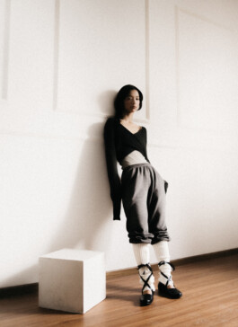 Model Tenzin Martha stands against a white wall in a contemporary fashion editorial for A Little Fly modeling agency, photographed by Sameer Khatri 