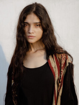 Portrait of model Deepika Sagar with long wavy hair, wearing a black top and embroidered shawl in soft natural sunlight 