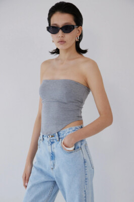 Fashion campaign portrait of model Ngawang Jinpa wearing a grey tube top, light blue denim jeans, and black sunglasses for Determ. 