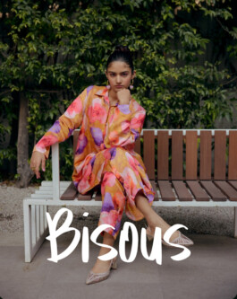 Model Aakriti Tyagi wearing a vibrant floral co-ord set seated on a bench for Norn’s Bisous campaign 