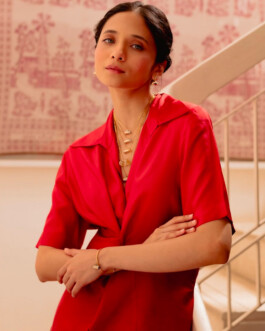 Indian model Anushree Vaze wearing layered gold necklaces and a red satin dress, posing for Moi Jewellery 