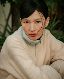 Ngawang Jinpa in a pale peach knit zip-up with a soft grey high-neck layer, styled by psuche 