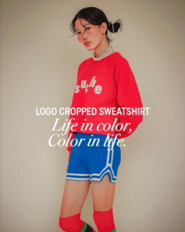 Ngawang Jinpa poses in a red cropped psuche sweatshirt with blue athletic shorts and red socks 