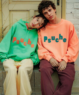 Ngawang Jinpa wearing a green hoodie with red psuche text, leaning on male model in peach sweatshirt 