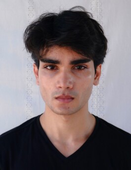 Front-facing digital of male model Prince wearing a black t-shirt against a white embroidered fabric background 