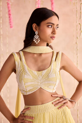 Close-up of model Dimple Aggarwal wearing a yellow embellished lehenga blouse with pearl earrings for Seema Thukral’s lookbook 