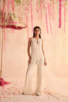 Model Dimple Aggarwal in an ivory embroidered kurta set with sheer dupatta by Seema Thukral, photographed under floral decor 