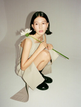 Ngawang Jinpa crouching with a white lotus in a neutral-toned outfit for Essential by EQL campaign 