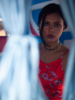 Ishra Philipose in red floral dress looking through blue curtains for Wasala fashion campaign 