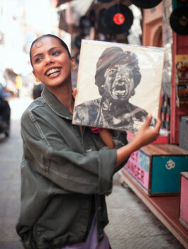 Ishra Philipose smiling and holding vintage record on street for Wasala campaign 