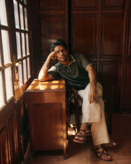 Man sitting pensively by a wooden desk with sunlight streaming in through French windows, photographed by ALF photographer Tenzin Lhagyal 