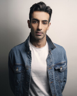 Editorial portrait of male model Vikas Mandaliya wearing a denim jacket over a white T-shirt against a neutral backdrop. 