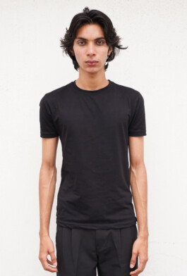Full body colour digital of Indian male model Shammazul Anas in black T-shirt and trousers against white wall 