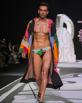 Vikas Mandaliya walking the runway for Shivan and Narresh in multicoloured swim briefs and coat during fashion week 
