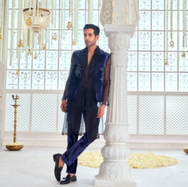 Vikas Mandaliya in royal blue velvet sherwani set by Abu Jani Sandeep Khosla, posing in ornate Indian interior with floral and chandelier décor 