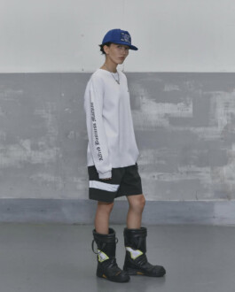 Ngawang Jinpa wearing Alfred SS25 oversized white long sleeve, black shorts, blue cap and statement boots in Seoul lookbook, represented by A Little Fly modeling agency India with Platinum Models 
