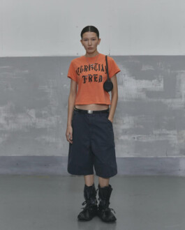 Ngawang Jinpa in Alfred SS25 lookbook wearing orange cropped t-shirt with bold print, navy shorts, and black boots, styled with Platinum Models Seoul for A Little Fly modeling agency India 