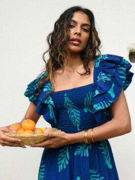 ALF model Shweta Poothery holding a basket of oranges while wearing a blue printed dress with ruffled sleeves for the Elisamama Campaign 