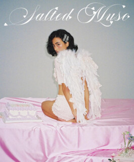 Medhavi Chettri wearing angel wings and a delicate white lace outfit, posing on a pink satin bed for the Salted Muse campaign; represented by ALF India modeling agency. 