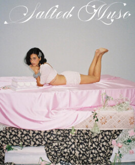 Medhavi Chettri lying on a pink satin bed setup with decorative flowers and a pastel cake for the Salted Muse campaign, represented by A Little Fly (ALF) India modeling agency. 