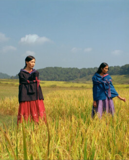 Two models standing in a golden rice field wearing layered Eka garments, photographed by Tenzin Lhagyal for ALF. 