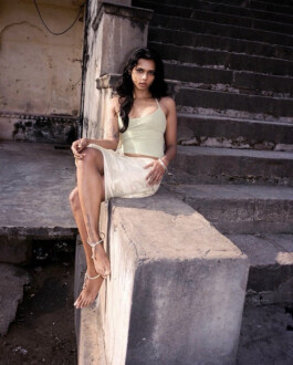 Female model seated on concrete steps wearing a light green tank top and skirt for Tank Air campaign, shot outdoors in natural light. Represented by ALF – A Little Fly, a leading modeling agency in India. 