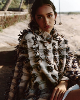 Model Theia Maeve wearing a textured handcrafted jacket in a warm-toned outdoor editorial for the Maatii Studio campaign. 